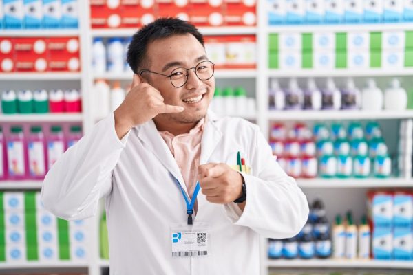 chinese-young-man-working-pharmacy-drugstore-smiling-doing-talking-telephone-gesture-pointing-you-call-me_839833-31061.jpg